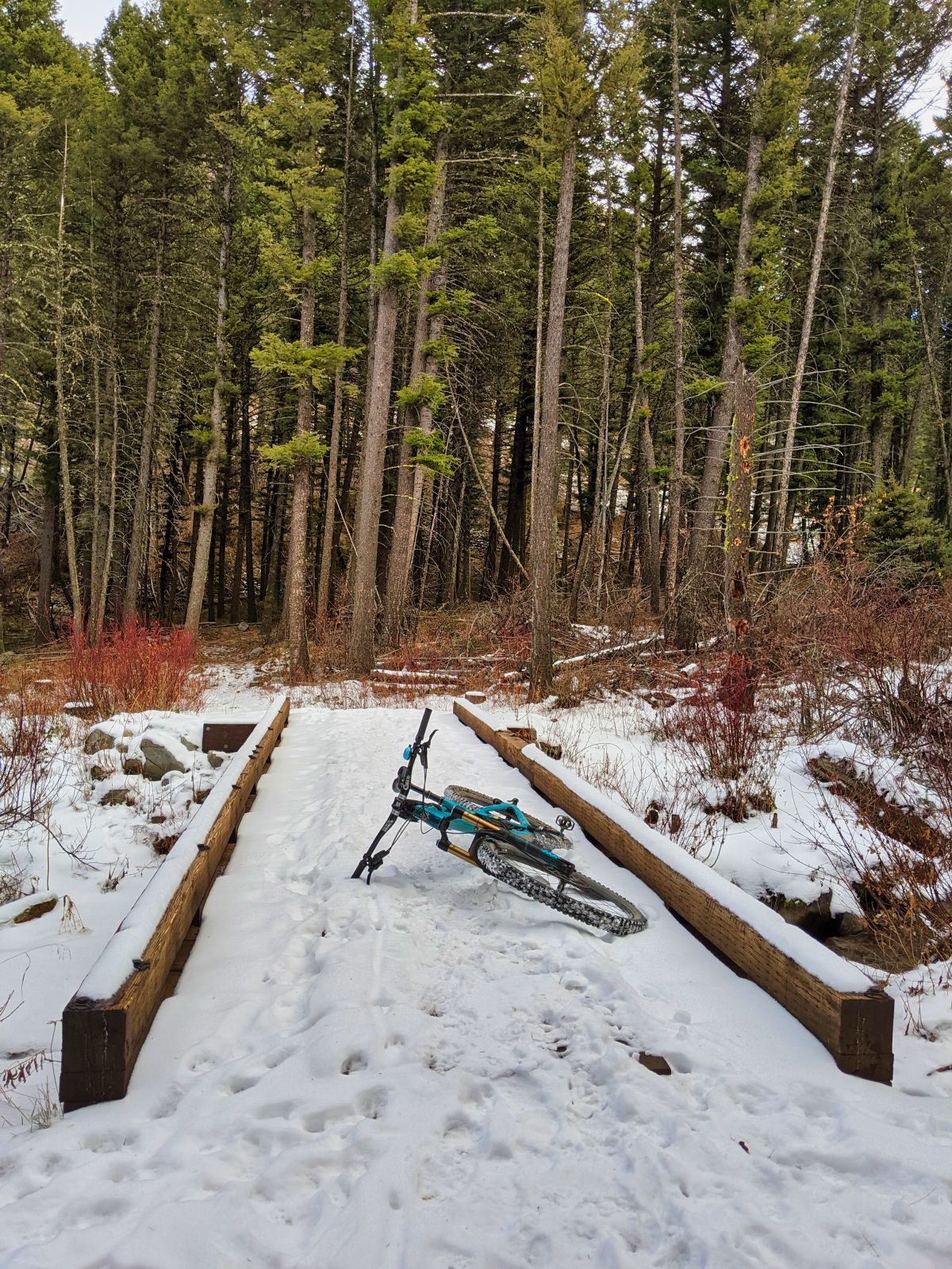 A Yeti SB6 enduro bike laying on a trail bridge in the snow